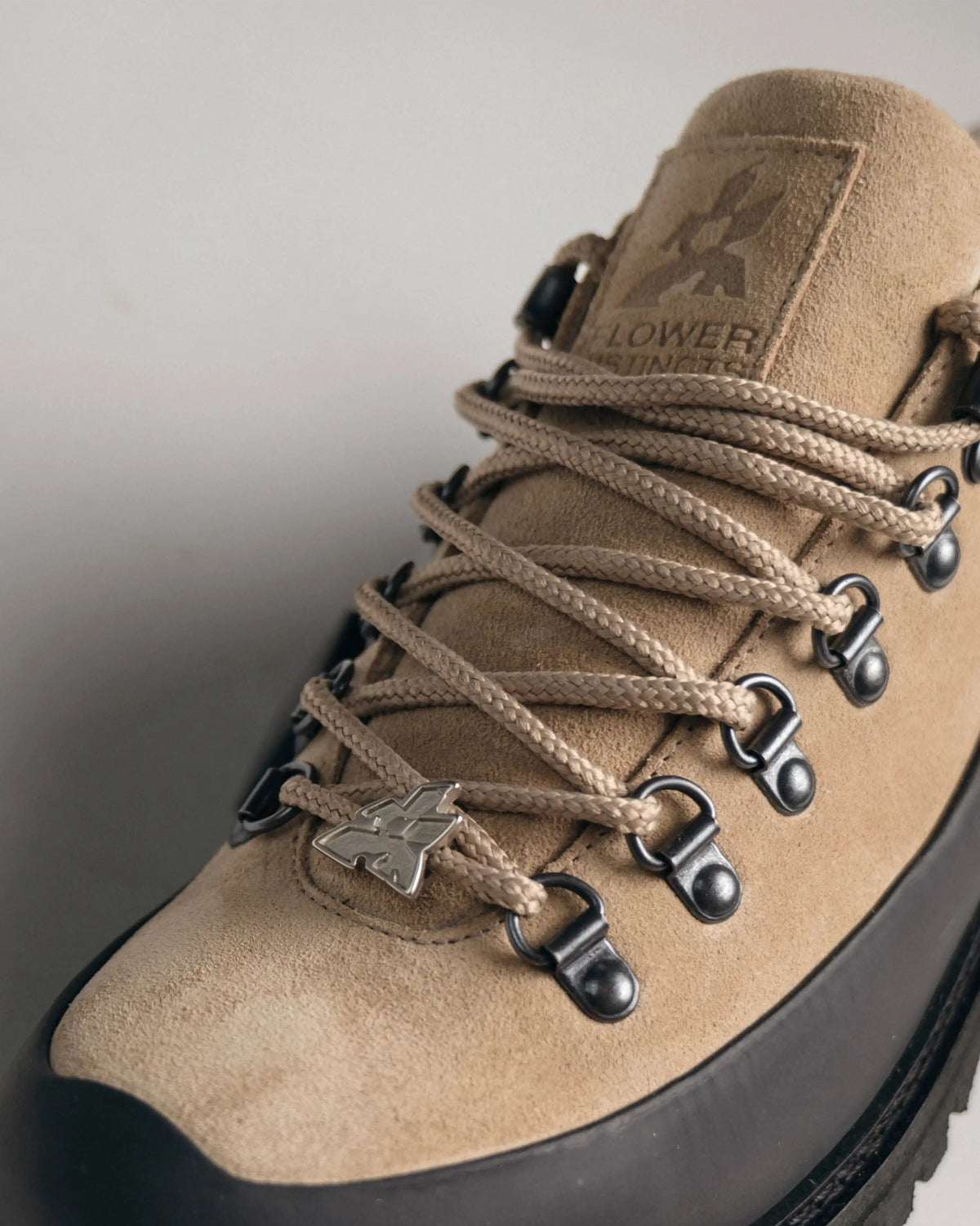A metal Flower tag on the lace, against beige suede. Handcrafted in Portugal.
