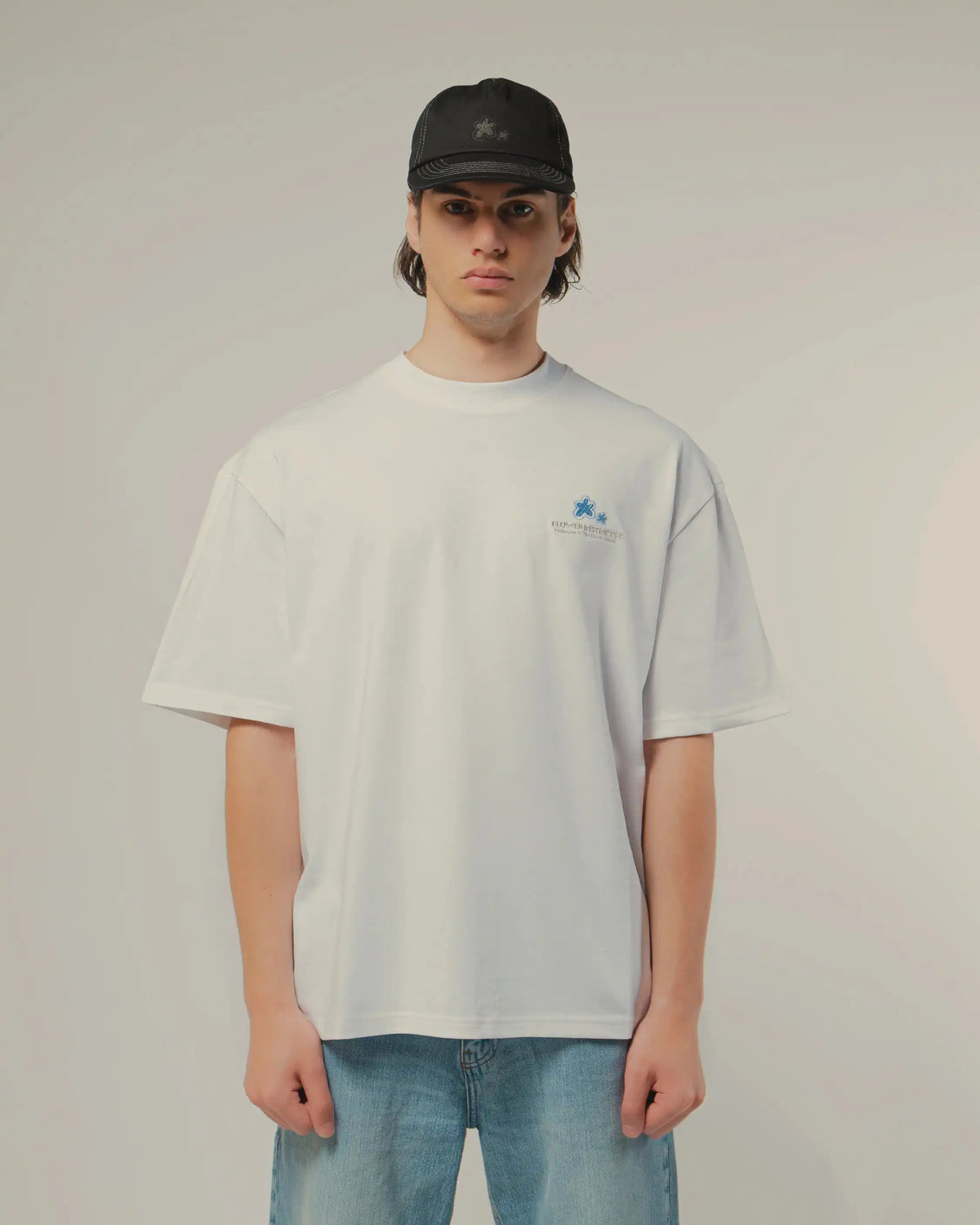 Tee 101 Crystal worn, front, small chest print, with a black cap